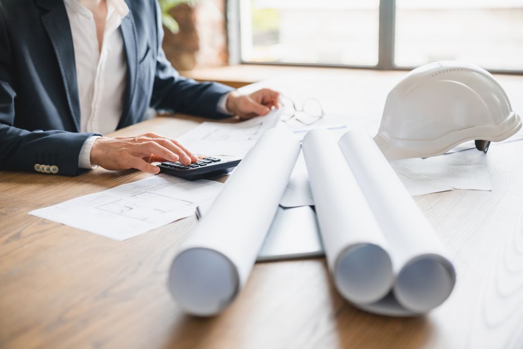 Closeup cropped male hands of businessman engineer architect working in office with blueprints, inspection in workplace for architectural plan, construction project. Construction industry